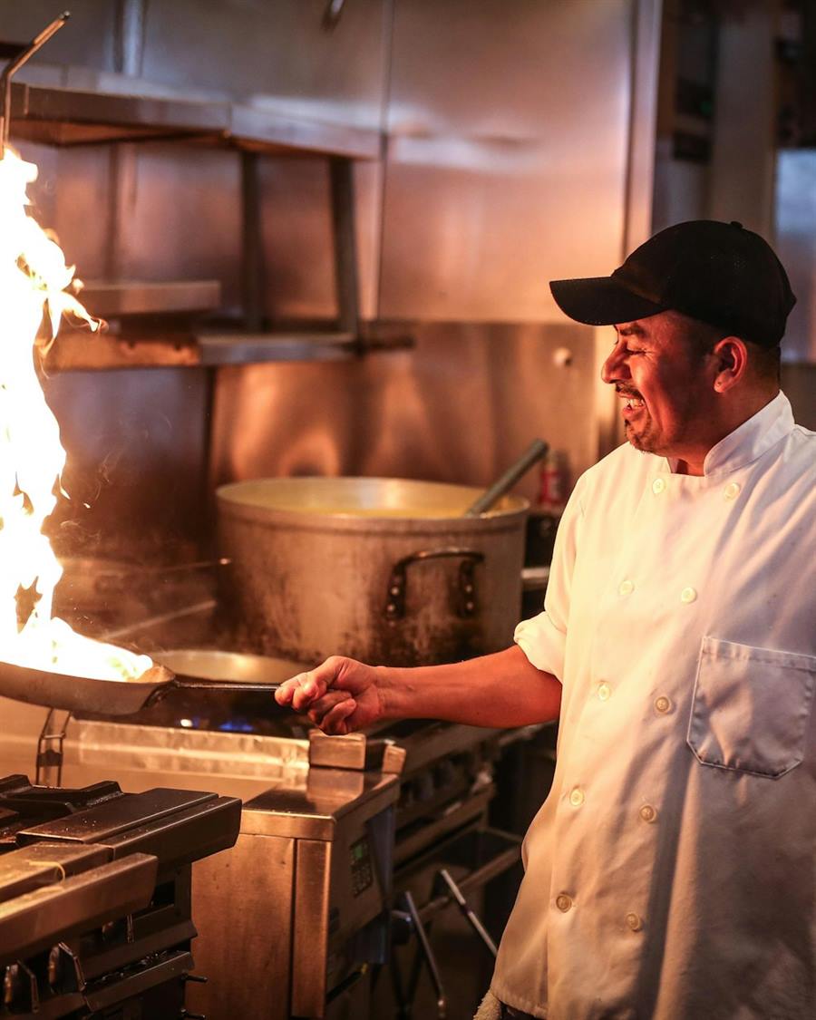 Illustrative image: a chef cooking in a stainless-steel professional kitchen.